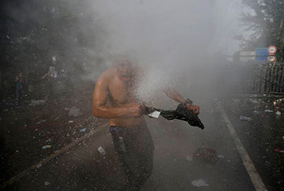 Agentes antidisturbios lanzan gas lacrimógeno y cañones de agua para evitar que sobrepasen desde Serbia su hermética frontera.