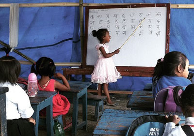 . Estudiantes de la escuela Dibya Jyoti de Bungamati dentro de un refugio provisional preparado por el equipo KUArt ‪#‎RebuildingBungamati‬. Algunas de las clases siguen dictándose en el edificio de la antigua escuela y el equipo está preparándose para más de estos albergues en los alrededores. La mayoría de los centros educativos en Nepal reabrieron la semana pasada después del devastador terremoto de abril. Desde entonces muchos edificios escolares no son seguros, las clases están dándose al aire libre y en algunos lugares, hasta dentro de construcciones peligrosas. 
